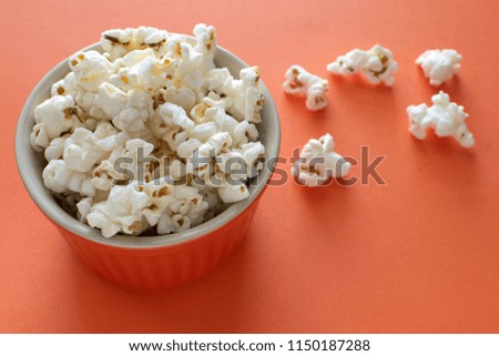 popcorn on orange background in an orange bowl