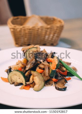 Pork roast with vegetables on white plate in table.