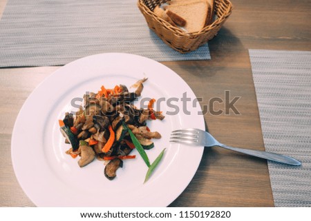 Pork roast with vegetables on white plate in table.