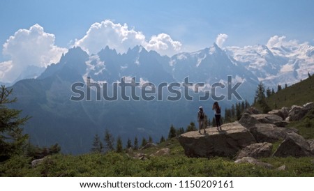 Females hikers enjoy the views of para gliders and the mountains over the valley of Chamonix, Ffrance and toward Mont Blanc in the french alps.