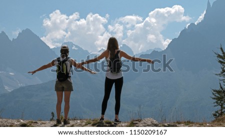 Females hikers enjoy the views of para gliders and the mountains over the valley of Chamonix, Ffrance and toward Mont Blanc in the french alps.
