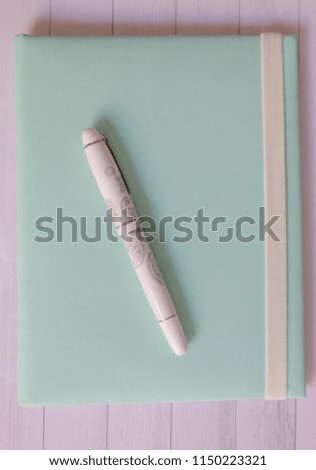 The handle and notebook against the background of a wooden table