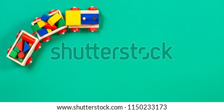 Wooden toy train with colorful blocks on green background Royalty-Free Stock Photo #1150233173