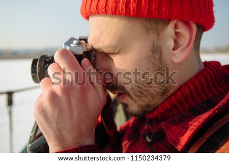Close up portrait of professional nature photographer outdoor in the winter and taking pictures with digital camera. Lifestyle and emotions. Wanderlust. Holiday. Christmas.