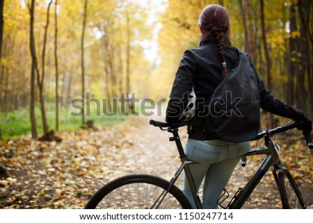 Photo from back of brunette in jeans next to bicycle