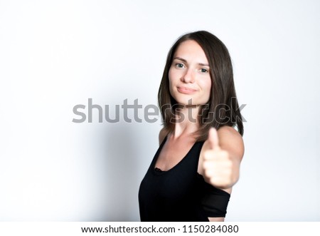 portrait of a young woman showing a thumbs up sign, like this, isolated studio photo on a gray background