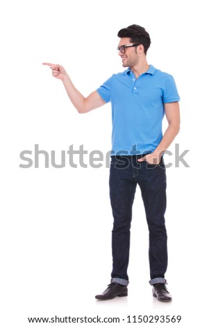 full body picture of a smiling casual man pointing to side on white background