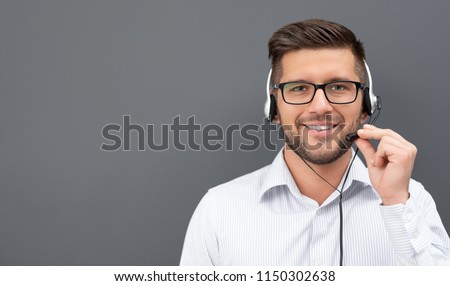 Call center worker isolated on a gray background. Smiling customer support operator at work. Young employee working with a headset. Royalty-Free Stock Photo #1150302638