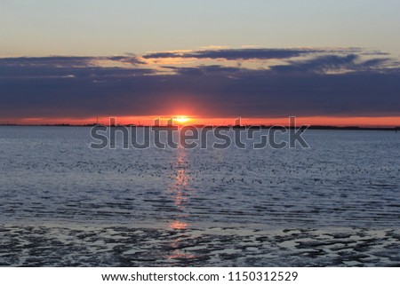 a beautiful sunset at sea at a hot summer day with a blue sky with big clouds and a rippling sea