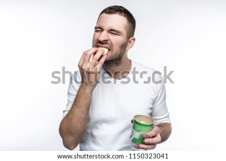 A picture of young nd weird man eating chips from the jar. This food is not healthy and good but he likes it. He is full of joy when he eats junk food. Isolated on white background.