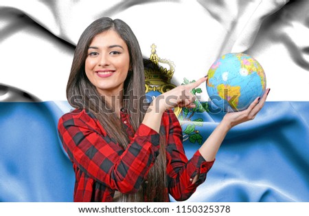 Young female Tourist holding Earth Globe against flag of San Marino