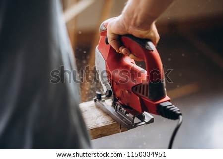 The carpenter, joiner, woodworker cutting the tree with an electric jig saw Royalty-Free Stock Photo #1150334951