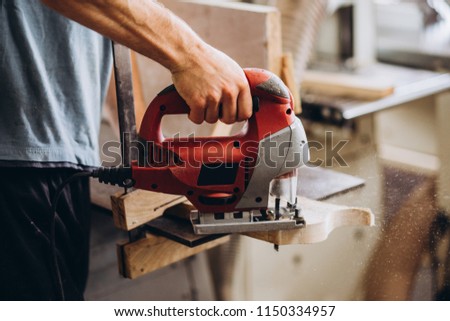 The carpenter, joiner, woodworker cutting the tree with an electric jig saw Royalty-Free Stock Photo #1150334957