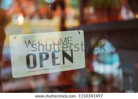 Business coffee cafe shop sign board is hang on door and show "Welocome We are open" with cafe and resturant blur bokeh background.