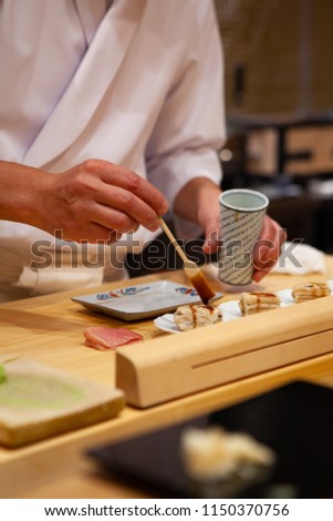 Professional and experienced sushi chef carefully add final touch with confident and dedication to his perfect sushi. Precision and Finesse at its best practice to achieve top performance in business.