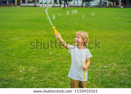 A boy blows bubbles against the grass