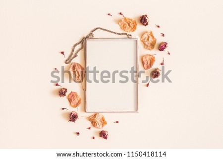 Autumn composition. Photo frame, dried flowers and leaves on pastel beige background. Autumn, fall concept. Flat lay, top view, copy space