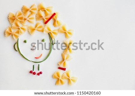 creative food concept, cute girls's face made of ripe vegetables and Italian farfalle pasta Royalty-Free Stock Photo #1150420160