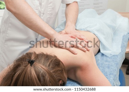 The doctor makes a body massage to a girl