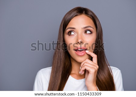 Portrait of brown-haired gorgeous nice curoius young lady showing thinking gesture with finger to lip, opened mouth, over grey background, isolated