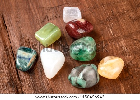 Semi precious gemstones on a dark wooden background with copy space. Emerald, selenite, jasper, kyanite, citrine, opal, jade, fluorite Royalty-Free Stock Photo #1150456943