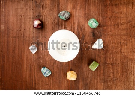 An overhead photo of gemstones around a candle. Healing stones with copy space. Emerald, selenite, jasper, kyanite, citrine, opal, jade, fluorite Royalty-Free Stock Photo #1150456946