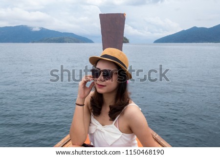 Front face view of the young woman wear hat with sunglasses in relax outside on the boat and looking at the sea view.