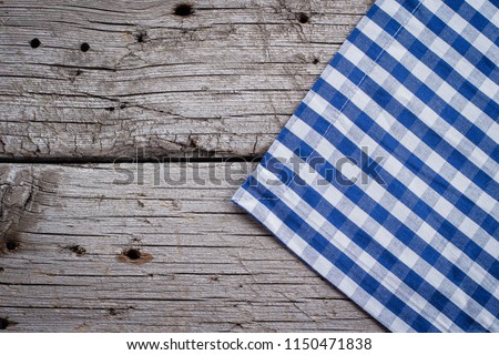 Blue checkered tablecloth kitchen towel on wooden rustic table background. Copy space, top view