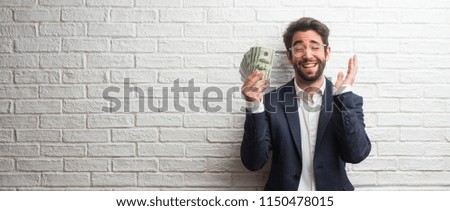 Young business man wearing a suit against a white bricks wall laughing and having fun, being relaxed and cheerful, feels confident and successful