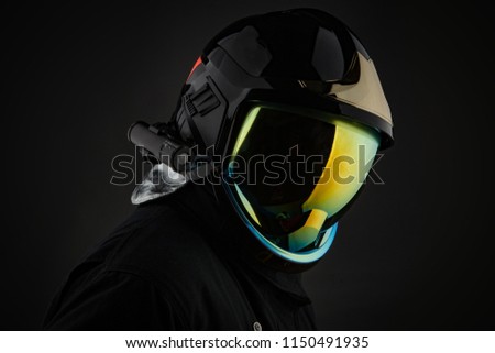 Unrecognizable firefighter in modern helmet on black background 