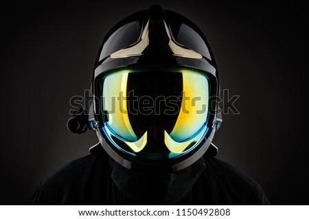 Unrecognizable firefighter in modern helmet on black background 