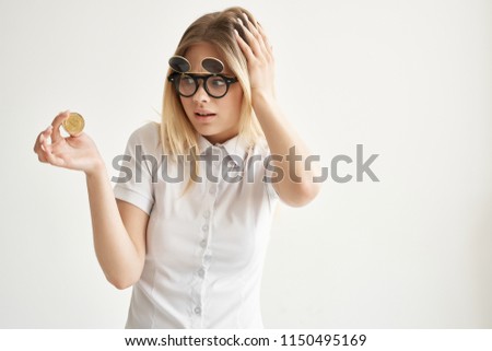 a woman in double-sided glasses looks at the coin in her hand in surprise                         
