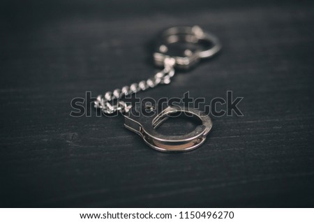 Law and Justice concept, Handcuffs on a black wooden background.
