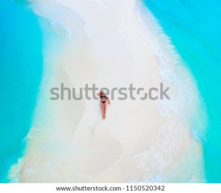 Beautiful woman tans on sandbank surrounded by turquoise ocean from above Royalty-Free Stock Photo #1150520342