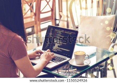 A female programmer typing source codes in a coffee shop with a relaxing working environment. Studying, Working, Technology, Freelance Work, Web Design Business, and Web Development Concept. Royalty-Free Stock Photo #1150524926