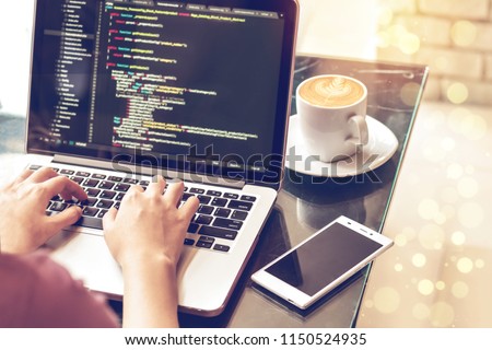 A female programmer typing source codes in a coffee shop with a relaxing working environment. Studying, Working, Technology, Freelance Work, Web Design Business, and Web Development Concept. Royalty-Free Stock Photo #1150524935