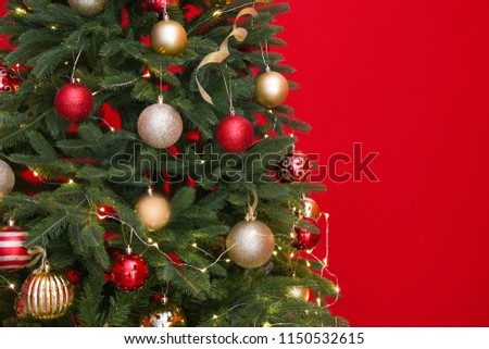 Beautiful Christmas tree with fairy lights and festive decor on red background