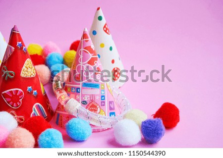 Colorful hats for birthday party decorations on pink background with copy space