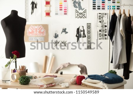 Creative fashion designer desk or workplace with sewing equipment, fabrics, templates, modern stylist inspirational office, dressmaker atelier with mannequin and clothes on hangers, couturier showroom