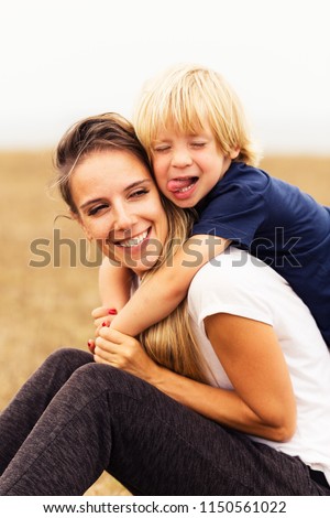 son embracing mom. mother and small kid sitting together outdoors. happy family spending time in park.
