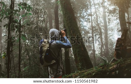traveler photographing with backpack and enjoying a beautiful nature forest. 