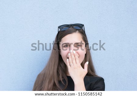 Portrait of shocked and surprised charming girl holding hand on mouth. Well-tended model posing for picture. Facial expressions concept. Isolated on blue background