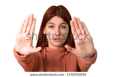 Young redhead girl with pink sweatshirt making stop gesture with her hand for disappointed with an opinion on isolated white background