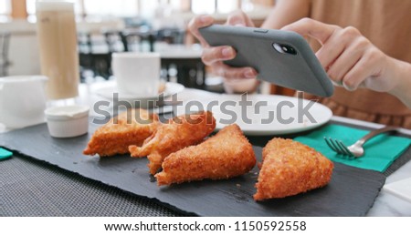 Woman taking photo on fried chicken wind in restaurant