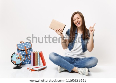 Young funny woman student in denim clothes hold book pointing index finger up blinking sit near globe, backpack, school books isolated on white background. Education in high school university college