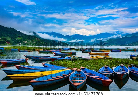 Colorful row boats docked on Lake Phewa in Pokhara, Nepal. Royalty-Free Stock Photo #1150677788