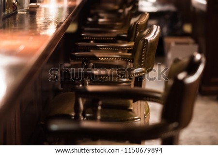 Bar design in classic vintage style. Oak wooden bar counter, comfortable chairs with leather upholstery and cooper rivets. Luxury interior. Great place for relax after work.  Royalty-Free Stock Photo #1150679894