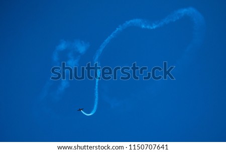 Aeroplane drawing a heart in blue sky during the show with tricks