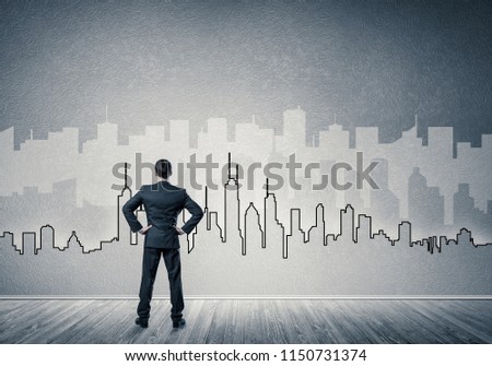 Businessman standing with back in concrete room with city silhouette on wall