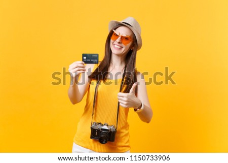 Traveler tourist woman in summer casual clothes, hat hold credit card isolated on yellow orange background. Female passenger traveling abroad to travel on weekends getaway. Air flight journey concept